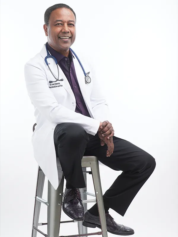 Guide To Headshots For Medical Professionals In Texas 2 Smiling male doctor in a white lab coat and stethoscope sitting on a stool.