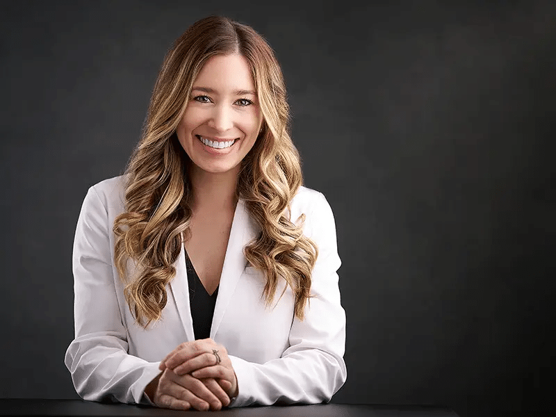 Guide To Headshots For Medical Professionals In Texas 3 Female doctor with long brown hair, smiling in a white coat.