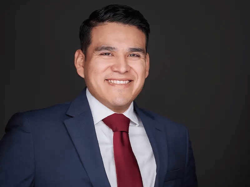 Man wearing a maroon tie with blue coat giving a professional pose